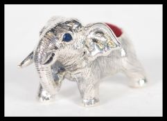 A sterling silver pin cushion in the form of an elephant having red baize pin cusion to top.