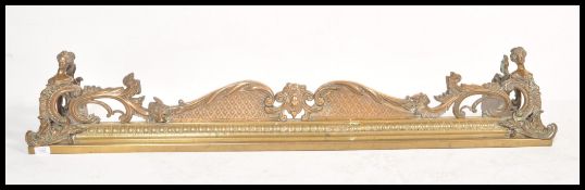 A 19th Century Victorian brass and bronze fire fender having brilliant figural finial ends in the