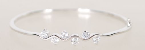 A sterling silver bangle bracelet having six claw set CZ white stones with hidden clasp to side.