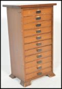 A mid century Industrial wooden pedestal filing cabinet having eleven drawers with ebonised pulls to