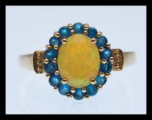 A hallmarked 9ct gold ring prong set with a oval cut yellow opalescent stone with a halo of blue