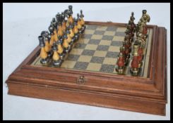 A 20th Century Chess set having a black and gold tone chess board set within a wooden frame with a