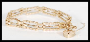 A hallmarked 9ct gold spacer bracelet with a heart lock and safety chain (AF). Hallmarked London