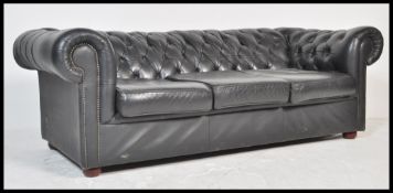 A contemporary black leather button back three seater Chesterfield sofa with button back and