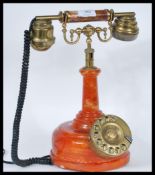 A vintage retro 20th Century ring dial stick telephone having orange stone effect body with ring