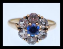 A stamped 9ct gold ring having a flower head set with white stones and a blue stone to the centre.