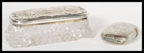 A silver hallmarked lidded cut glass dressing table trinket pot having relief decoration of