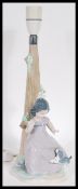 A Lladro Nao ceramic figurine table lamp in the form of a girl playing with a dog, Printed and