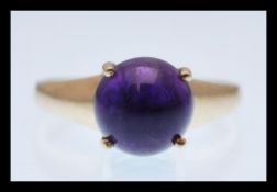 A hallmarked 9ct gold ring set with a purple cabochon stone. Hallmarked Birmingham 2005. Weight 3.