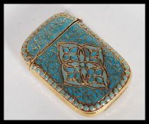 A brass and enamel vesta match case in the Anderson style having hinged lid and scrolled