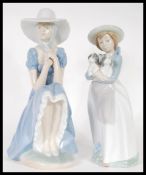 Two Nao porcelain ceramic figures of girls to include a girl seated in a bonnet together with a girl