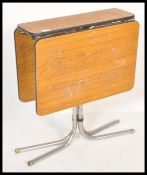 A retro tmid century teak formica and chrome drop leaf dining table being raised on tubular chrome