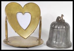 A 20th Century brass trench art swing photo frame in the form of a heart raised on a round base