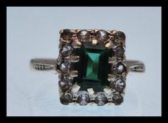 A hallmarked 9ct gold ring set with a square green stone and white accent stones. Hallmarked london.