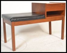 A vintage teak wood telephone table having a telep