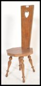 A early 20th century spinning chair raised on turned legs having a pierced heart handle to the