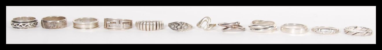 A group of twelve sterling silver rings to include Russian trilogy puzzle ring, band ring with white