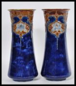 A pair of early 20th Century Royal Doulton tapering cylindrical stoneware vases decorated with Art