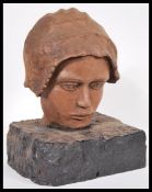 A 19th Century carved wooden bust head of a child wearing a bonnet raised on ebonised wooden