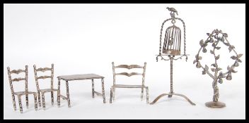 A collection of silver dolls house miniature furniture to include a table and chairs having a turned