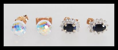 A pair of stamped 375 9ct gold earrings set with oval cut sapphires with a halo of diamonds, along