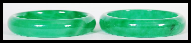 A true pair of 20th Century Chinese green jade bangle bracelets of circular form in a deep green
