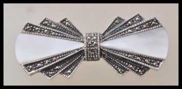 A silver Art Deco style brooch in the form of a bow tie set with marcasites and mother of pearl