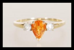 A hallmarked 9ct gold ladies dress ring set with a tear drop cut orange stone flanked by two white