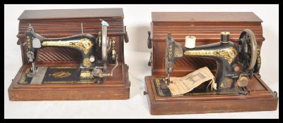 Two early 20th century hand crank Singer sewing machines, both machines with wooden carry cases and