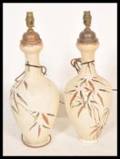 A pair of early 20th Century ceramic table lamp vases having hand painter floral sprays and