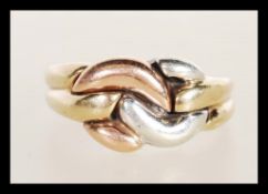 A hallmarked 9ct gold ring having a three tone gold knot design to the head. Hallmarked
