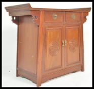 A 20th Century Chinese hardwood cabinet with altar design top, drawers over two plain panelled