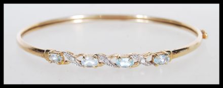 A 9k stamped 9ct gold bangle bracelet set with illusion set diamonds and faceted prong set blue