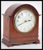 A 20th Century mantel clock having a mahogany case of domed form with a round white enamelled