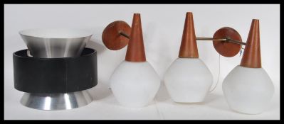 A vintage retro 20th Century wall light having a circular teak wall mounts with two brass arms and