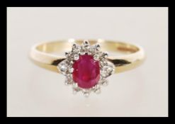 A hallmarked 9ct gold diamond and garnet flower head ring having a central faceted red stone with