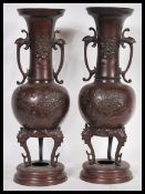A pair of 19th century Japanese bronze vases of baluster form having twin scrolled handles with