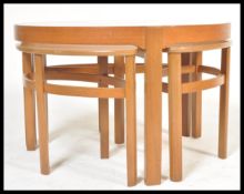 A retro 1970's Nathan teak and glass Trinity quartetto nest of table being raised on shaped legs