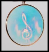 A 9ct gold roundel pendant inset with hologram of musical notes together with a 9ct chain.  The