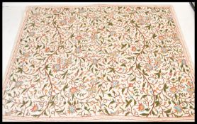 A 20th Century embroidered crewel work throw blanket on a woven white fabric ground with embroidered