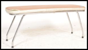 A 20th Century vintage retro bench having a beige vinyl padded seat being raised on four chromed
