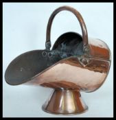 A 19th Century Victorian copper coal scuttle of helmet form raised on conical pedestal base with