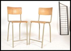 A pair of vintage retro 20th Century tubular stacking chairs having plywood seats and backrests.