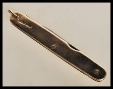 A 1920's 9ct gold cased penknife with engine turned decoration, having two folding blades within.