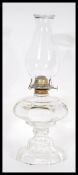 An late 19th / early 20th Century oil lamp having a clear glass and brass fittings with a flu