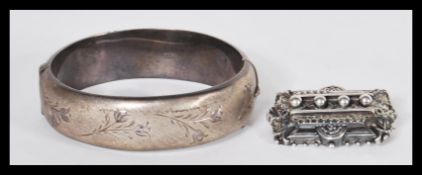 A vintage hallmarked silver bangle bracelet having half engraved floral decoration with hidden clasp