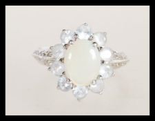A hallmarked 9ct white gold opal and white stone cluster ring having a central opal panel with a