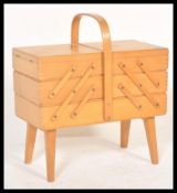 A vintage retro 20th Century teak wood cantilever sewing box having metamorphic action raised on