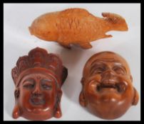 A group of three Japanese wooden hand carved netsukes to include a Meiji period Buddha head