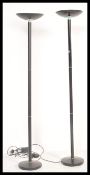 A pair of 20th Century ebonised tubular up-lighter standard floor lights / lamps being raised on